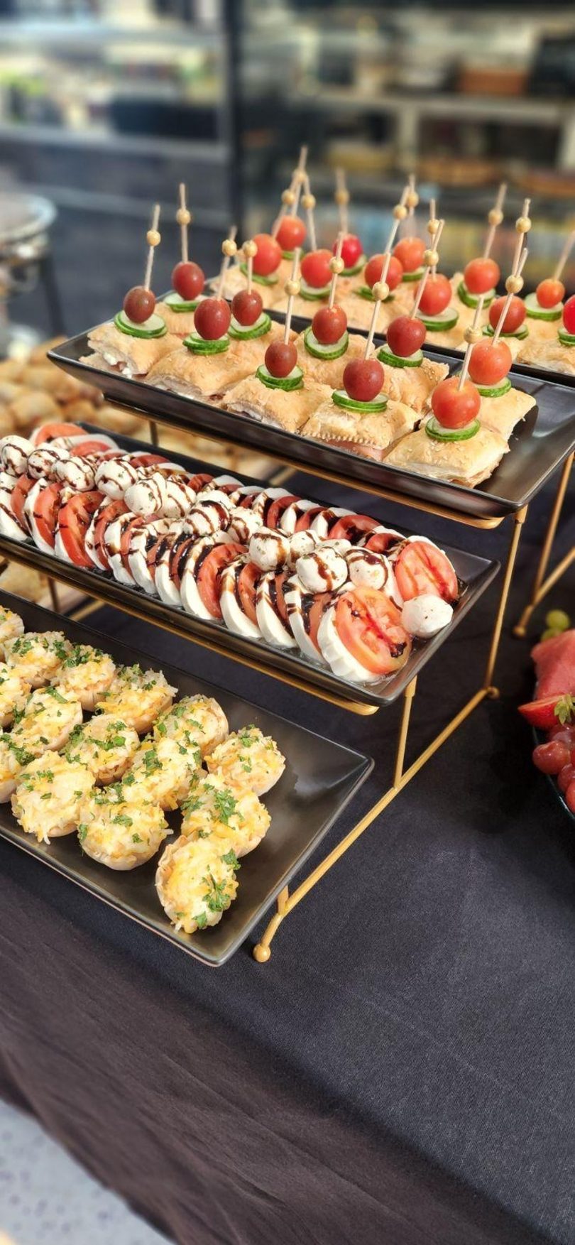 Three tiers of appetizers, including tomato and mozzarella, puff pastry bites, and stuffed mushrooms.