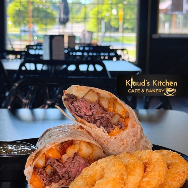 Two steak and potato burritos with cheese, a side of onion rings, and a dipping sauce.