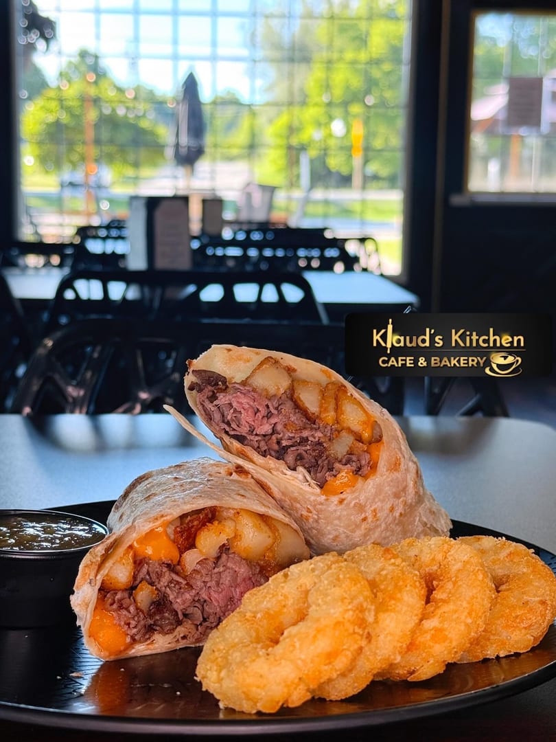 Two steak and potato burritos with cheese, a side of onion rings, and a dipping sauce.